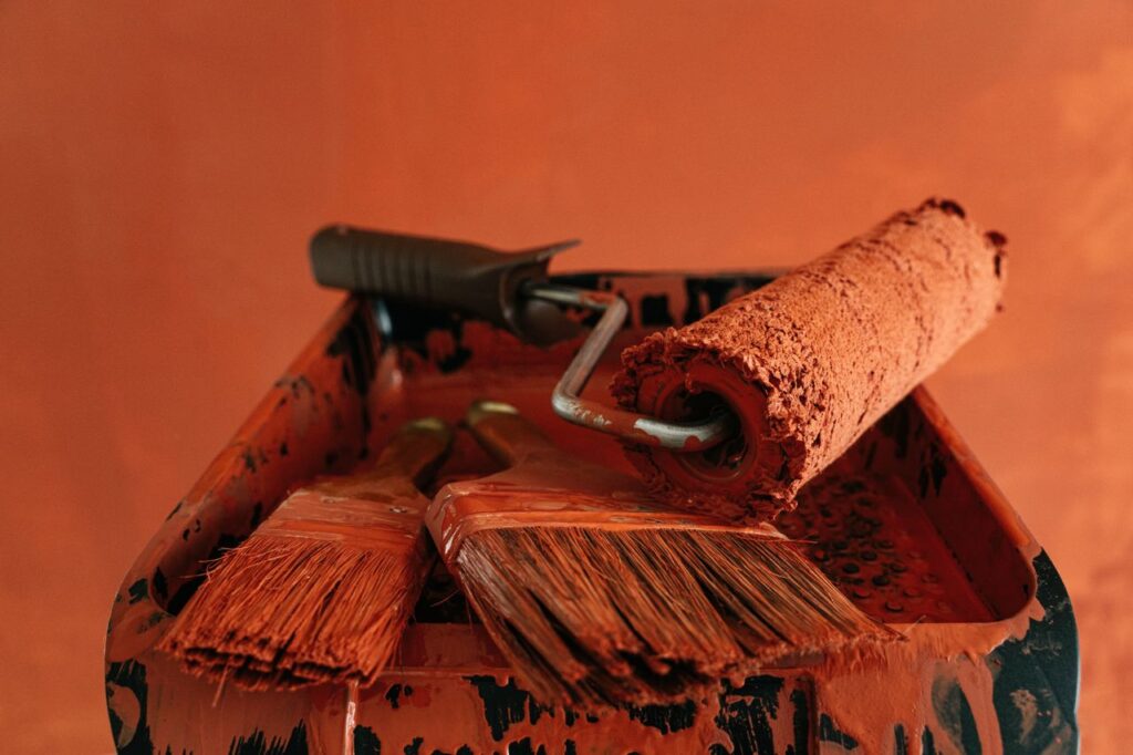 Orange paint tools in a messy tray, perfect for renovation themes.
